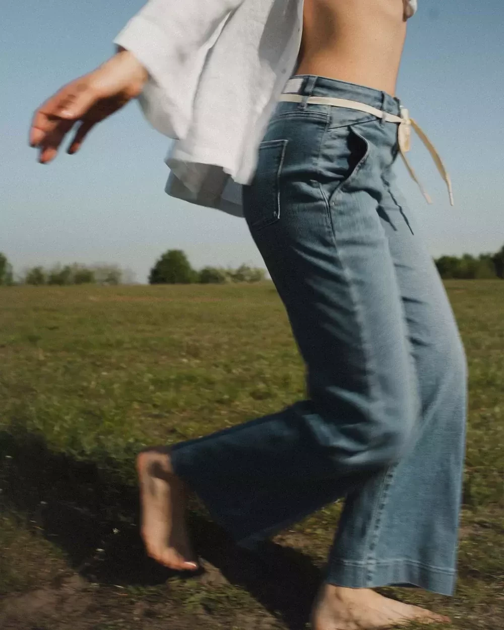 Ein Bild einer Frau mit Dawn Denim läuft über eine Wiese.